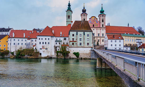 Panoramic view of the Zwischenbrücke bridge crossing the clear Steyr River towards the historic St. Michael's Church (Michaelerkirche) and old town buildings in Steyr, Austria