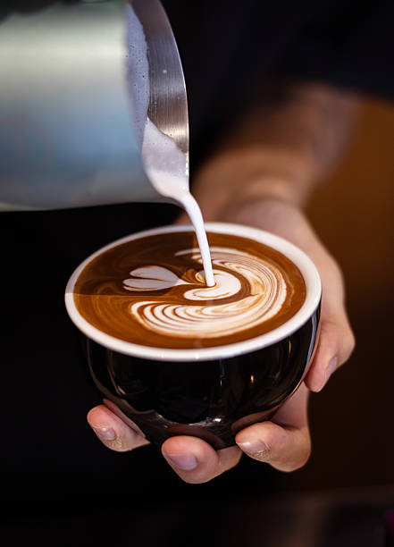 Unrecognizable man is holding chocolate mocha coffee at coffee shop.Preparing fresh coffee with froth art.
