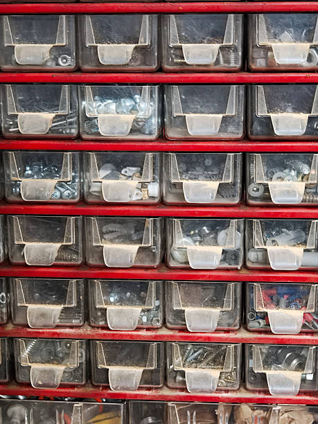 Organized red storage cabinet full of transparent drawers containing an assortment of metallic screws, nuts, bolts, and small hardware, crucial for repair and diy projects