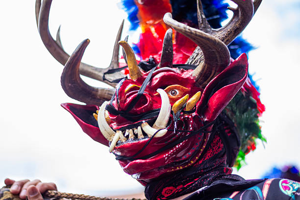 Diablada dancer wearing a traditional ecuadorian devil mask with prominent horns, tusks, and vibrant feathers, representing folklore and cultural heritage during the pillaro carnival