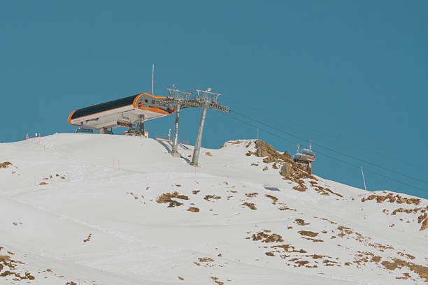 Red Ski lift in the background of the winter mountains. An elevator raises people against the backdrop of mountains, among the clouds, between pines and fir trees. Fairy mysterious unusual look.