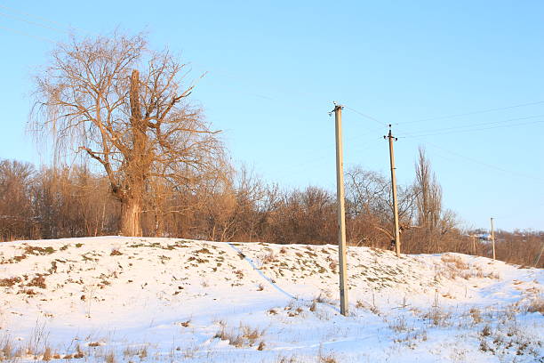 A snowy field with power lines. Snow. Sky. Outdoor. Nature. Day