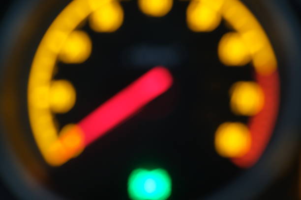 A detailed view of a car speedometer illuminated with bright orange lights, various dashboard indicators