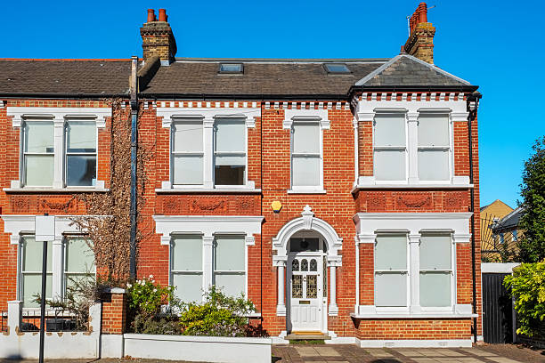 London, UK - 30 October, 2025: exterior architecture of a charming old traditional end-of-terrace row house in Hampstead, London. The property is Georgian in style and has a bright yellow front door, and a cute little front garden.