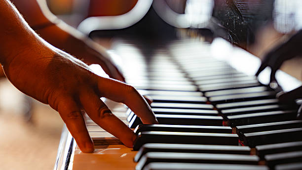 Person's hands gently pressing white and black keys on a piano keyboard