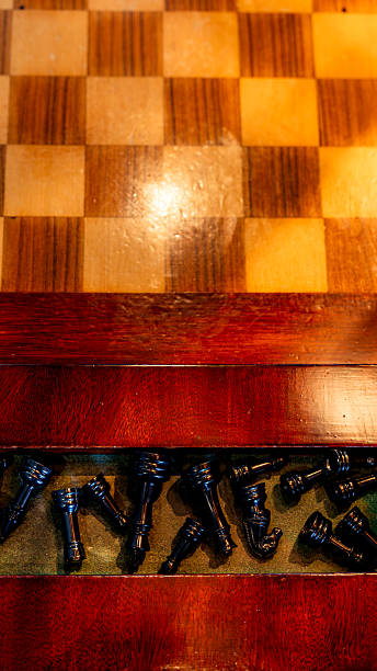 Chessboard showing checkered pattern with many black chess pieces stored in a wooden box