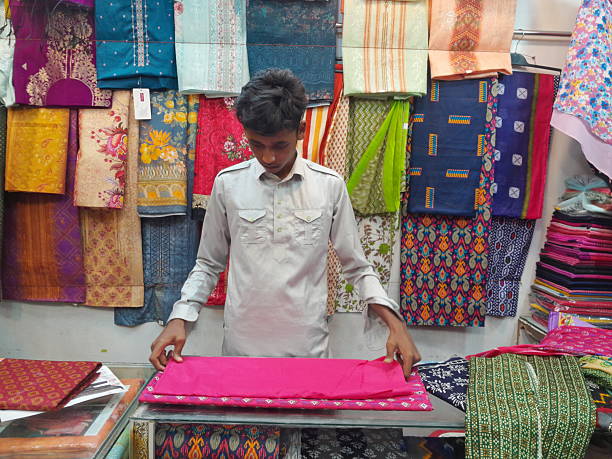 Cumilla, Bangladesh - June 16, 2023: A vendor with Handloom saree fabric material in his clothes store.