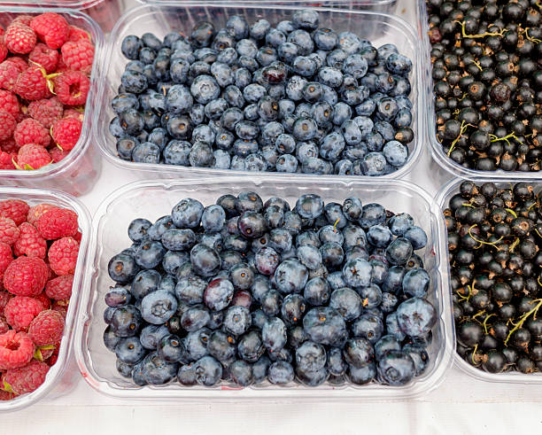 blackberries and strawberries as well as blueberries in plastic are packaged in small plastic boxes for sale on the market. top view.