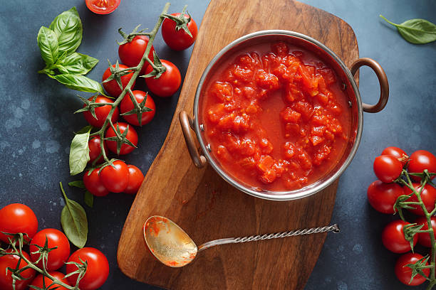 Homemade tomato sauce with basil leaves on blue background. Chopped tomatoes for italian sauce. Top view. Copy space.