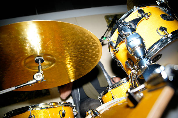 Musician drumming a yellow percussion set, creating rhythm and music