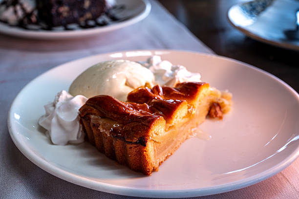 A slice of homemade apple pie served with a scoop of vanilla ice cream on a decorative plate, photographed from above on a rustic wooden table.