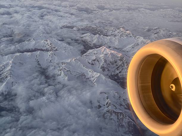airplane engine over snow covered peaks, sunlit turbine casting warm glow on metal, rugged mountain ridges
