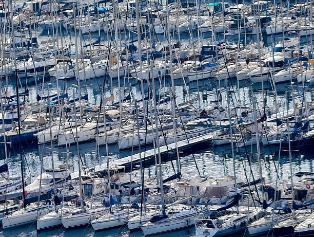 Aerial view dense sailboat masts forming pattern, packed berths creating geometric rhythm with repeating