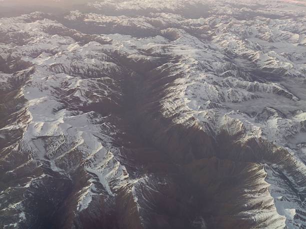 Aerial view snowcovered mountain valley with jagged ridgelines and deep shadowed canyons, expedition mapping