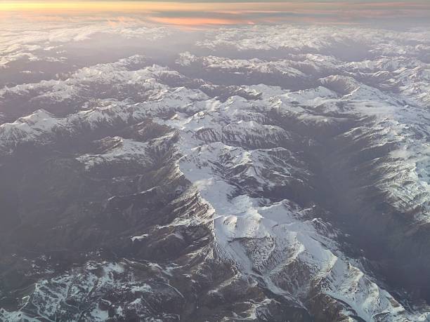 aerial sunlit mountain ridge at dawn golden light casts long shadows across snowfields, crisp crests
