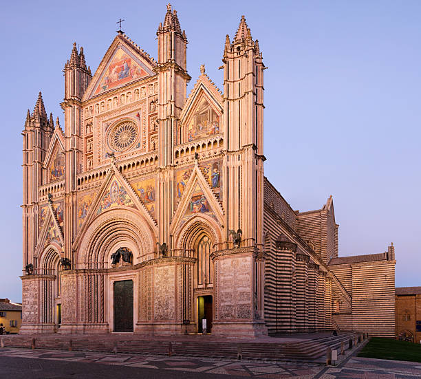 Orvieto Cathedral, also known as the Duomo di Orvieto, at twilight in the town of Orvieto, Umbria, Italy. Built between the 13th and 14th centuries, the Gothic cathedral is known for its richly decorated façade, mosaic details, and prominent rose window.
