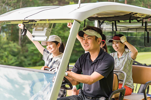 Two Caucasian friends golfers, male and female, are riding around the golf court in the golf cart during sunset