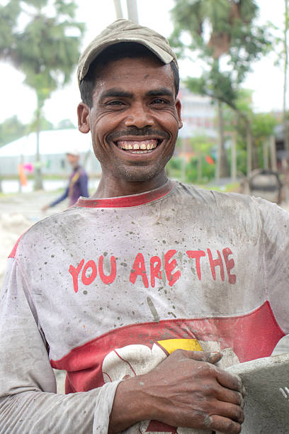 A worker smiles by looking at camera