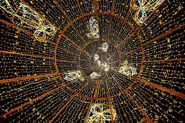 A view up at a decorative dome illuminated with thousands of warm lights and holiday ornaments. The scene creates a magical atmosphere, suitable for Christmas and New Year campaigns, holiday events, city decoration and winter festivals.
