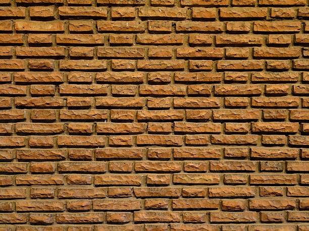 orange brick wall texture detail shows weathered clay bricks with deep mortar lines, warm tones and subtle