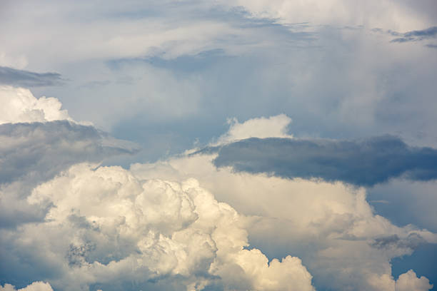Dramatic clouds fill the blue sky, creating an atmospheric backdrop. Various shapes and sizes of clouds enhance the serene daytime outdoor scene.