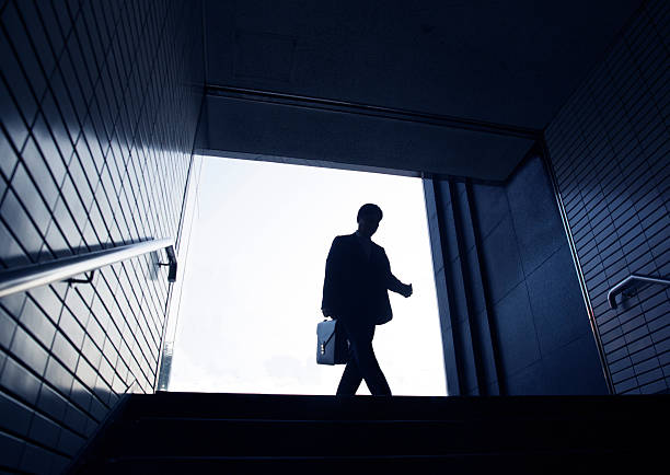 Silhouette of a man standing on a black surface on a white background.