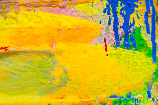 Dynamic abstract composition of multicolored acrylic paint splatters and streaks in green, yellow, blue, orange, pink, and purple on canvas, creating a lively textured surface perfect for contemporary art backgrounds and creative design elements.