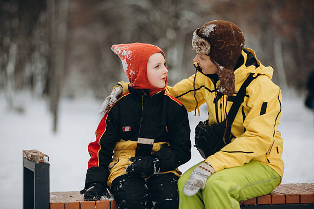 Mother and son sitting on a bench in a snowy park, enjoying a winter outing and sharing a warm moment