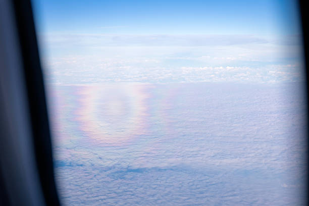 A circular rainbow is visible from an aircraft flying north of Tenerife in the Canary Islands. The atmospheric phenomenon, often observed from above the clouds, forms a complete ring due to the angle of sunlight and the observer’s elevated position. The scene documents an aerial perspective on natural optical effects.