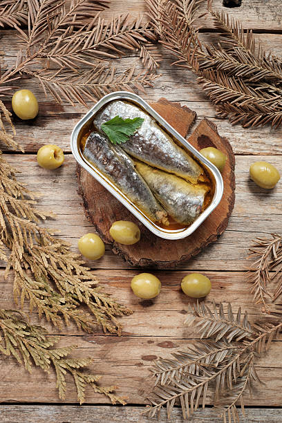 Sardines in Oil Placed on Wooden Surface With Olives and Leaves Around