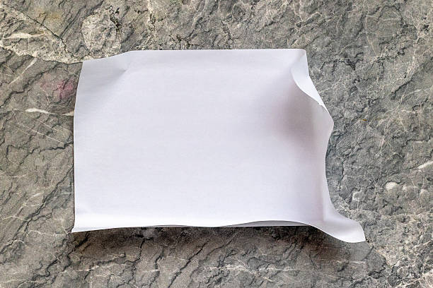 Blank white paper sheet on marble surface with textured background.