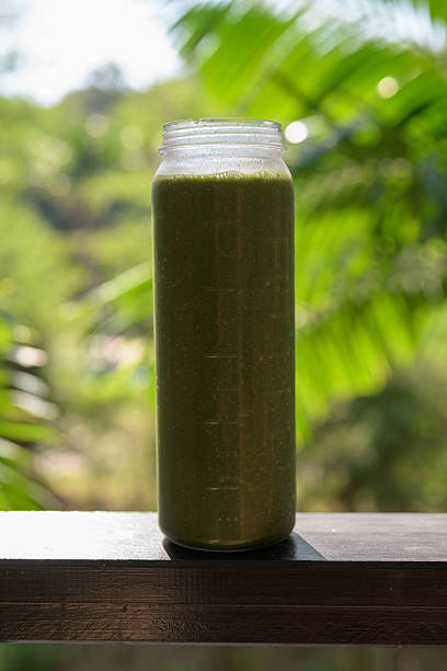 Green Smoothie Bottle with Tropical Leaves Background for Healthy Lifestyle Concept