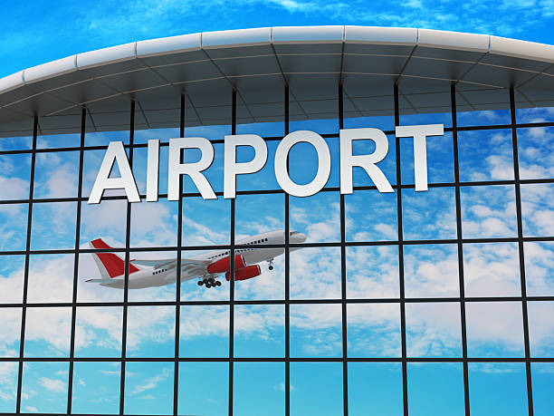 A modern airport terminal with a glass facade reflecting the sky as an airplane takes off. Digitally generated image