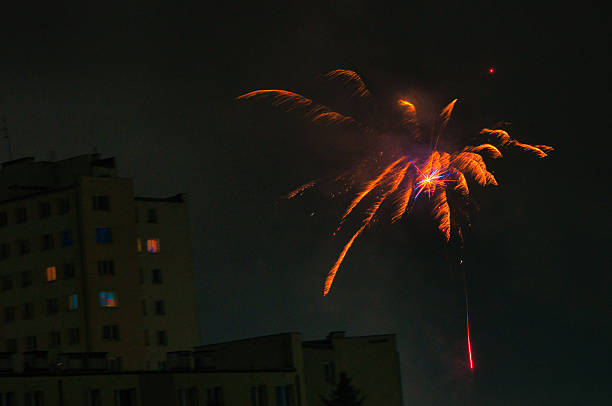 The night is illuminated by multicolored, vibrant fireworks, sparkling orange with green accents. Perfect for backgrounds and textures, event marketing, and festive images that convey energy and emotion.