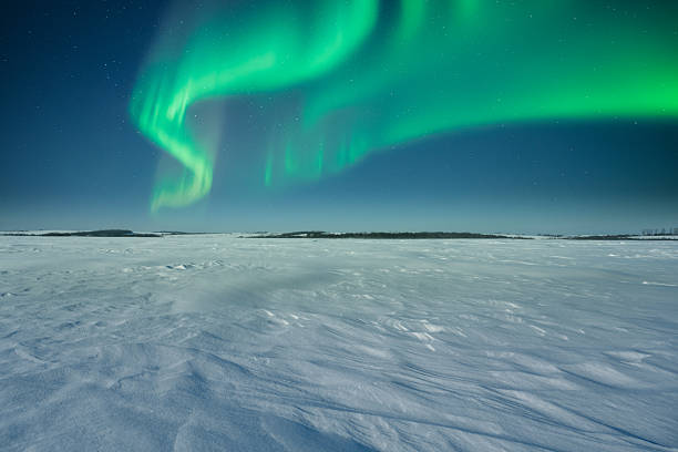 Open snowy wilderness under glowing northern lights and stars, winter night sky, arctic landscape photography