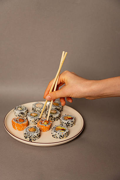 hand using chopsticks to take sushi from plate copy space isolated