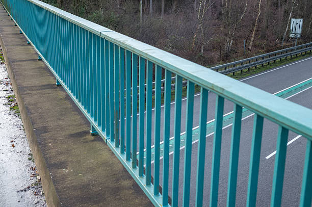 Teal painted metal railing on a concrete overpass above rÃ¶merseestraÃe in heiden, germany