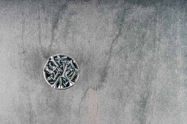 A small bowl of metal screws on a gray surface, perfect for industrial or DIY projects