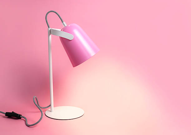 Modern table lamp on pink background flat lay. Lighting, lamp, light, interior decor, electricity. Children's pink table lamp. Single piece of furniture. Metal designer lamp.