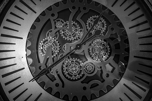 Detailed monochrome photograph of a mechanical clock face revealing intricate gears and moving components. This image highlights precision engineering, craftsmanship, and the timeless concept of time, making it ideal for editorial, conceptual, industrial, and fine art use.