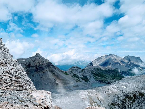 A series of stunning views from the Gemmi Pass (2,350m) near Leukerbad in the Valais Alps. The photographs capture the rugged limestone peaks, the tranquil waters of the Daubensee, glacial plains, and traditional stone cairn waymarkers under a summer sky.