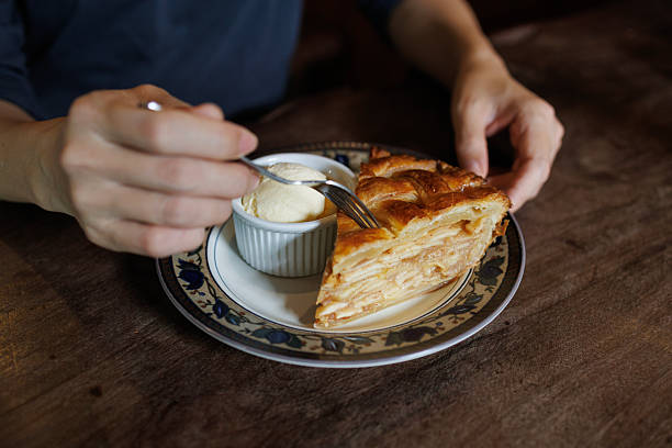 Person Enjoying Apple Pie with Vanilla Ice Cream at a Cafe Table