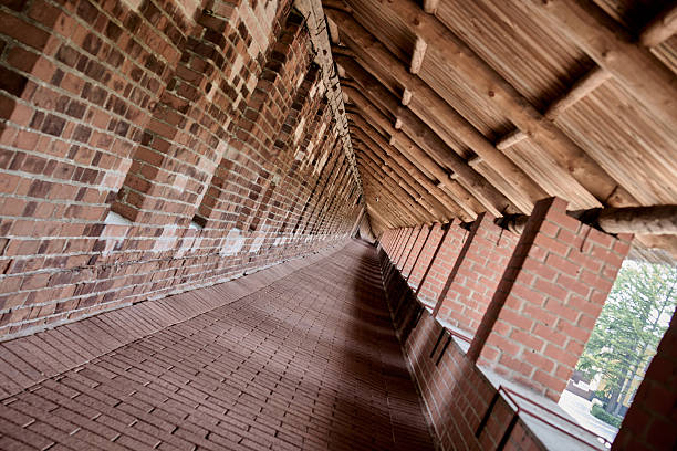 Long, dark brick tunnel narrowing towards a distant light source, creating a deep perspective