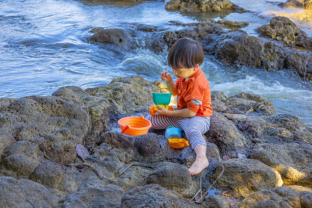 Kid, baby, toddler playing by the stream, connect with nature. Net Zero, Carbon Neutral.
