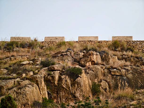 rocky escarpment dotted with masonry blocks ideal for geological survey and fieldwork with layered strata,