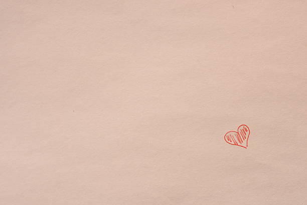 Red heart drawn with a pen on white paper, slightly filled in, placed in the bottom right corner.
