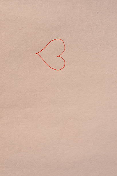 Small red heart drawn with pen on white paper, placed on the left, centered vertically. Minimal horizontal background with ample copy space.