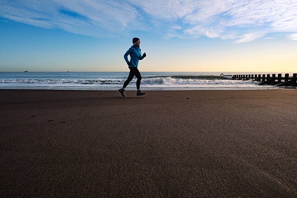 Senior woman running on the beach just north of Aberdeen, Scotland, as dawn breaks. With the tide going out, the sand is free of footprints.