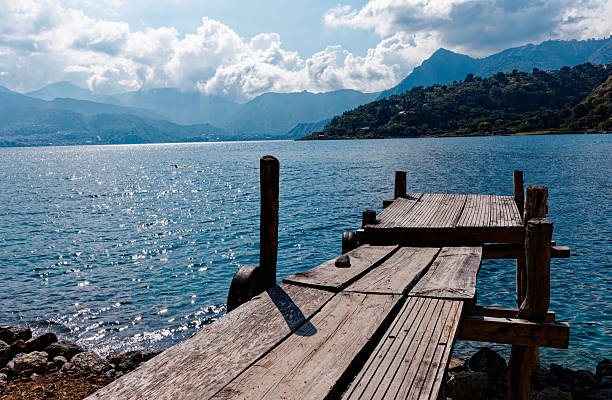 Young Caucasian woman  sitting on pier on Atitlan Lake in Guatemala at sunset