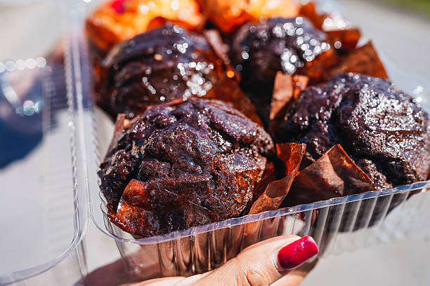 Woman's hand holding a box of chocolate muffins